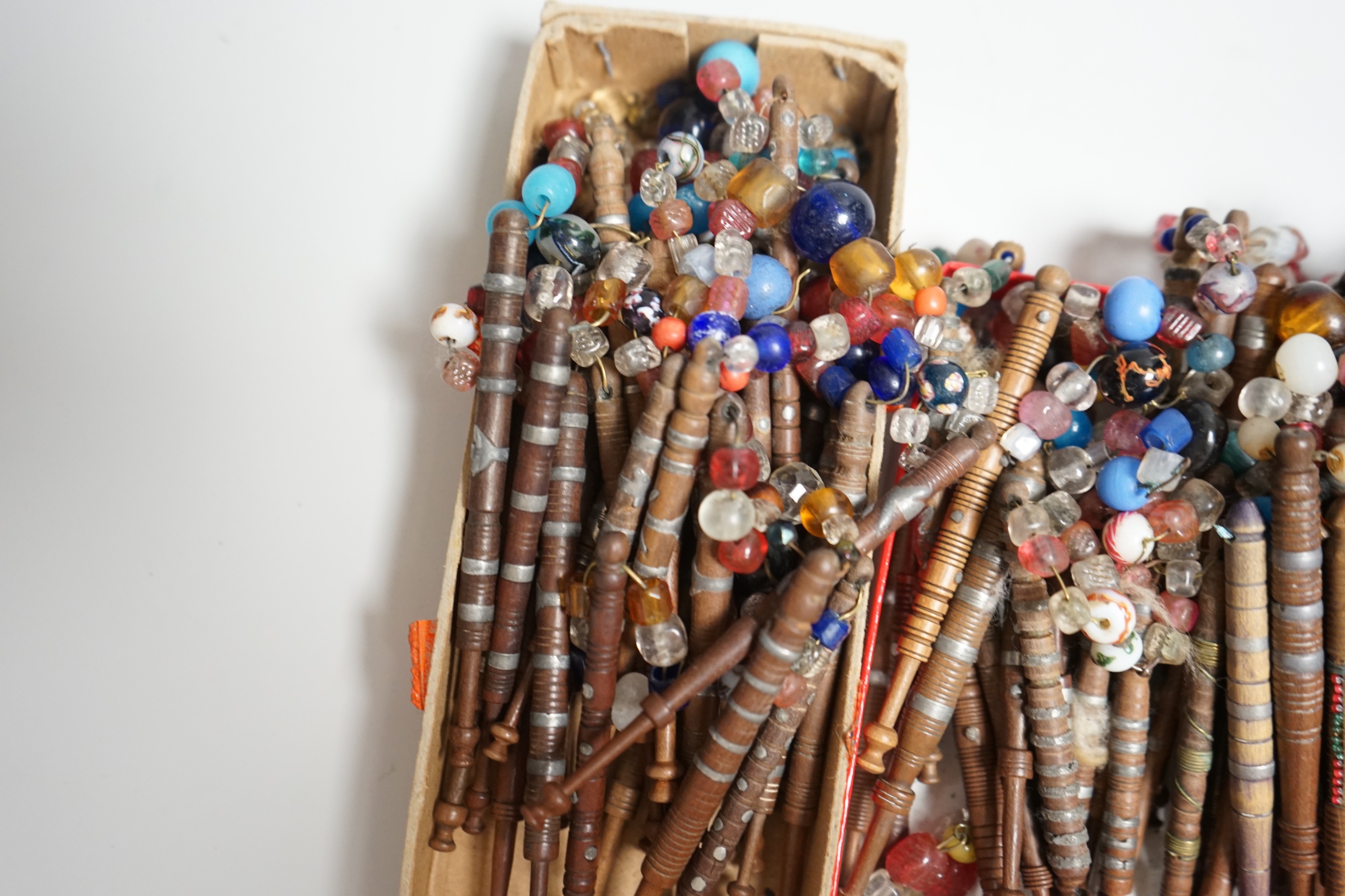 Eighty 19th century wood and metal decorated lace bobbins with coloured beaded tops